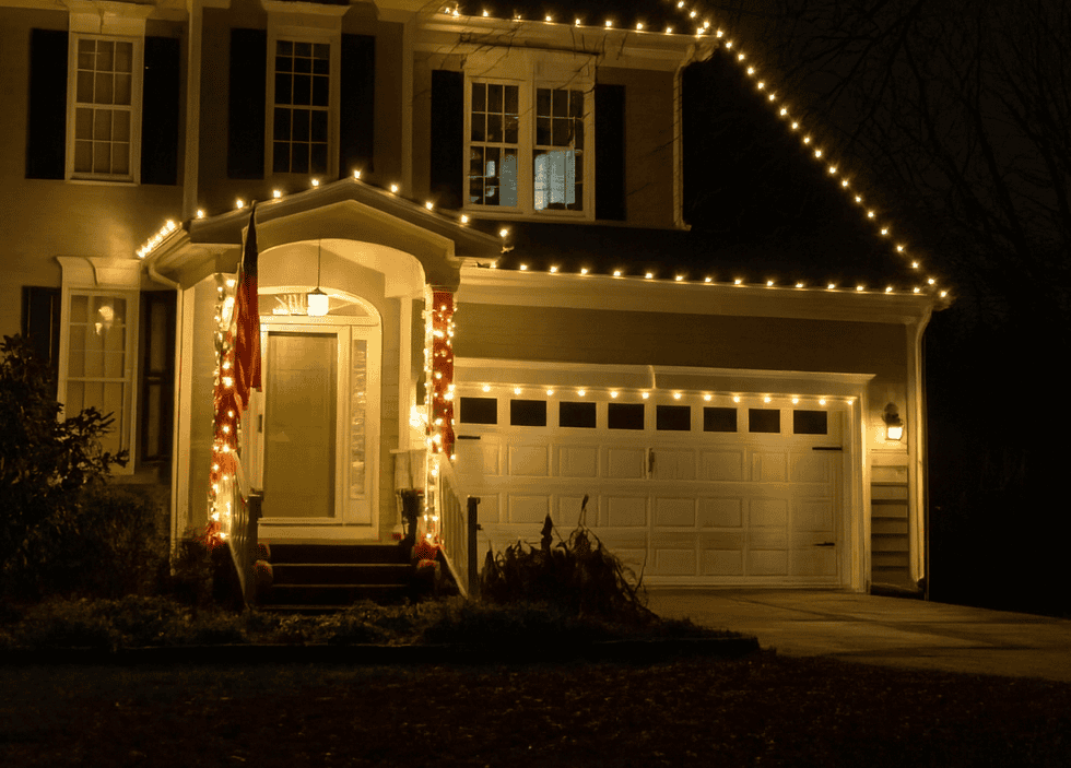 Professional vs. DIY Christmas Light Installation Two-story home at night with warm white C9 lights along every roofline, the front entry, and above the garage